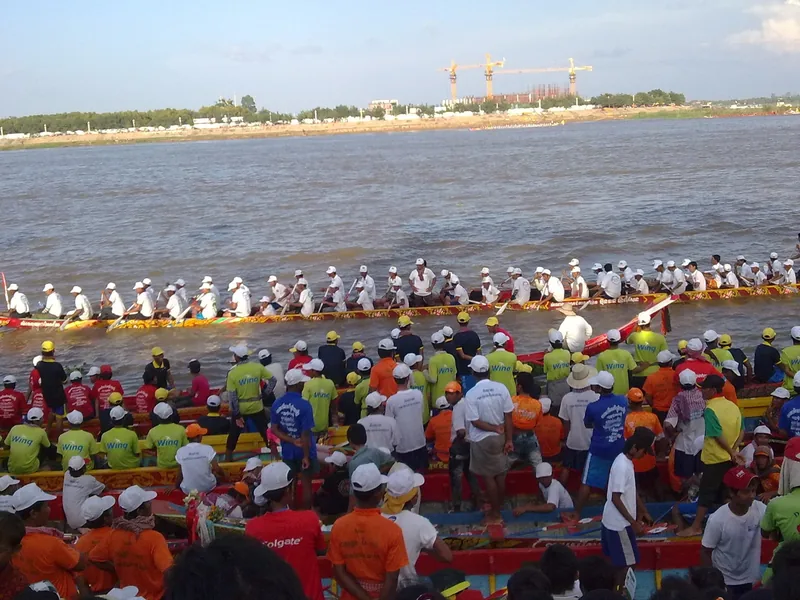Long dragon boat teams in colorful jerseys row across the wide river during a water festival in Phnom Penh.