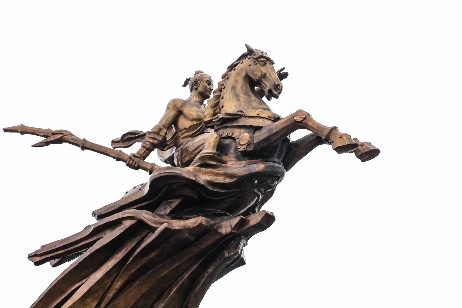A bronze equestrian statue of a warrior wielding a spear atop a rearing horse against a bright sky in Hanoi. A bronze equestrian statue of a warrior wielding a spear atop a rearing horse against a bright sky in Hanoi.