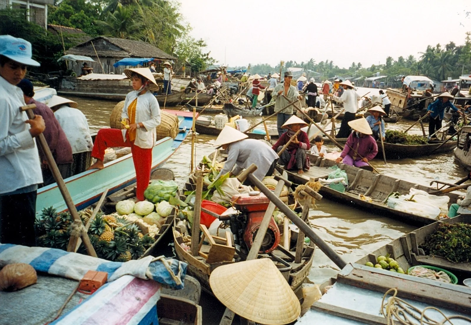 Boats loaded with fruit and vegetables crowd together at a bustling floating market in the Mekong Delta