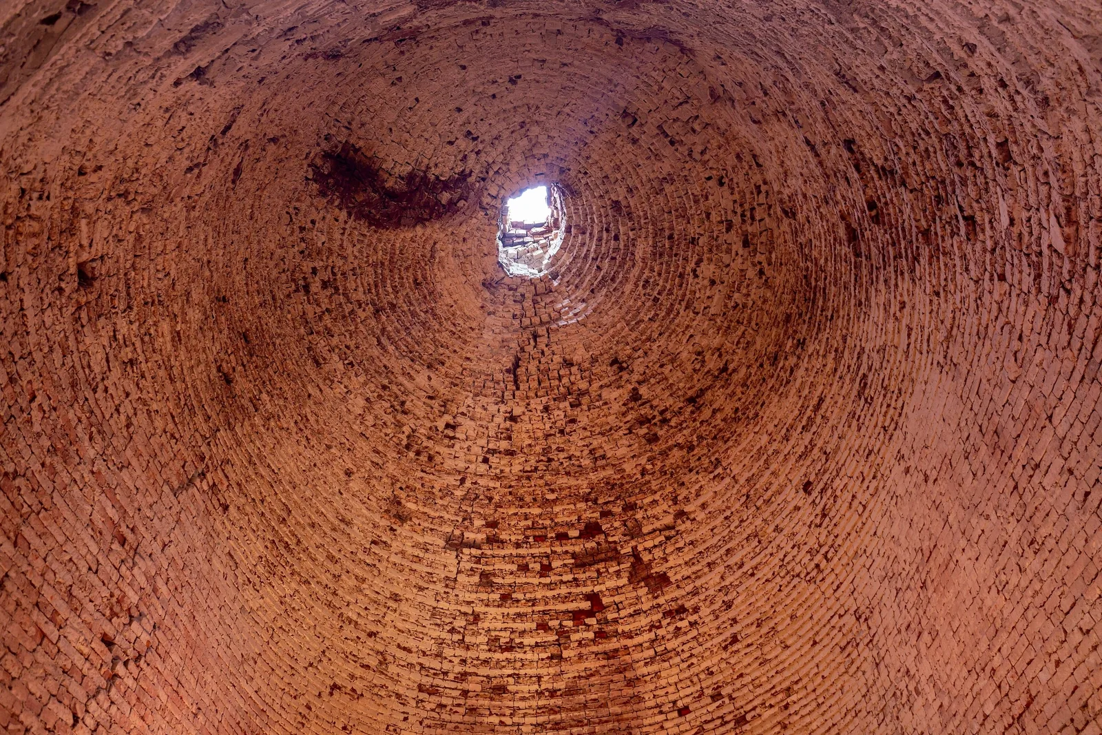 Looking up inside a tall brick kiln in the Mekong Delta, its curved walls spiraling toward a small opening of light. Looking up inside a tall brick kiln in the Mekong Delta, its curved walls spiraling toward a small opening of light.