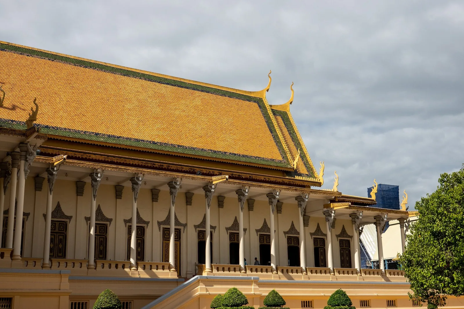 Golden tiled roof and columned facade of the Throne Hall at the Royal Palace in Phnom Penh.